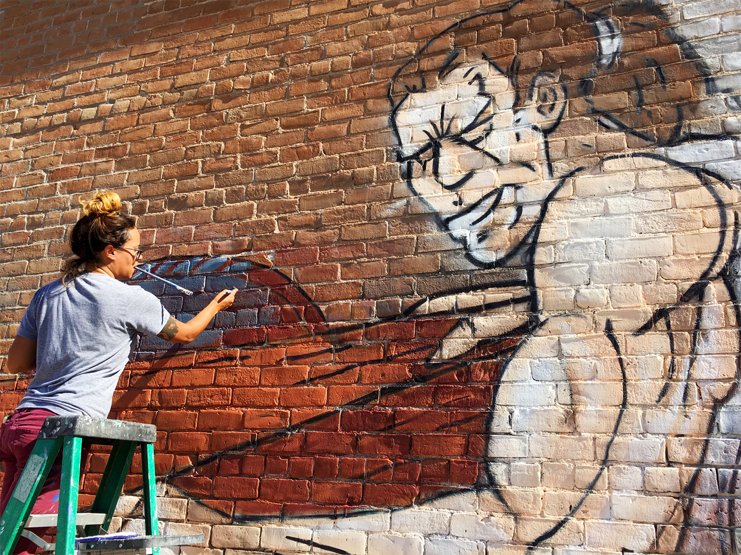 Artist Allison Miller painting a mural