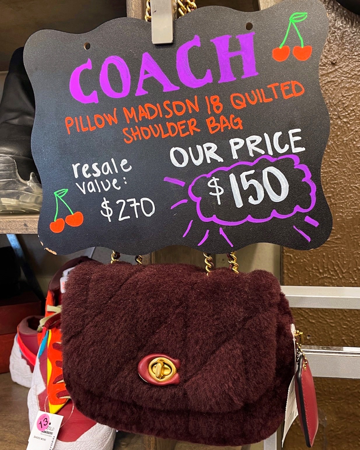 2024.02.11 TX1 Sign above a handbag reads "Coach Pillow Madison 18 Quilted Shoulder Bag Resale Value $270 Our Price $150"