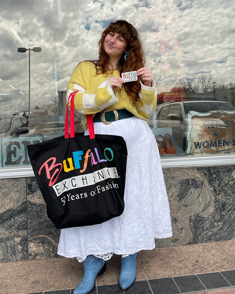 customer-with-card Smiling woman holds Buffalo Exchange gift card and tote bag