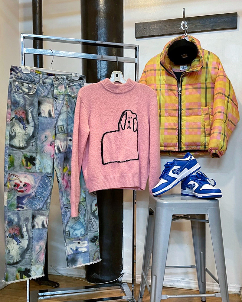 employee-picks Rack of clothing with jeans, sweater, jacket and a pair of sneakers sitting on a stool