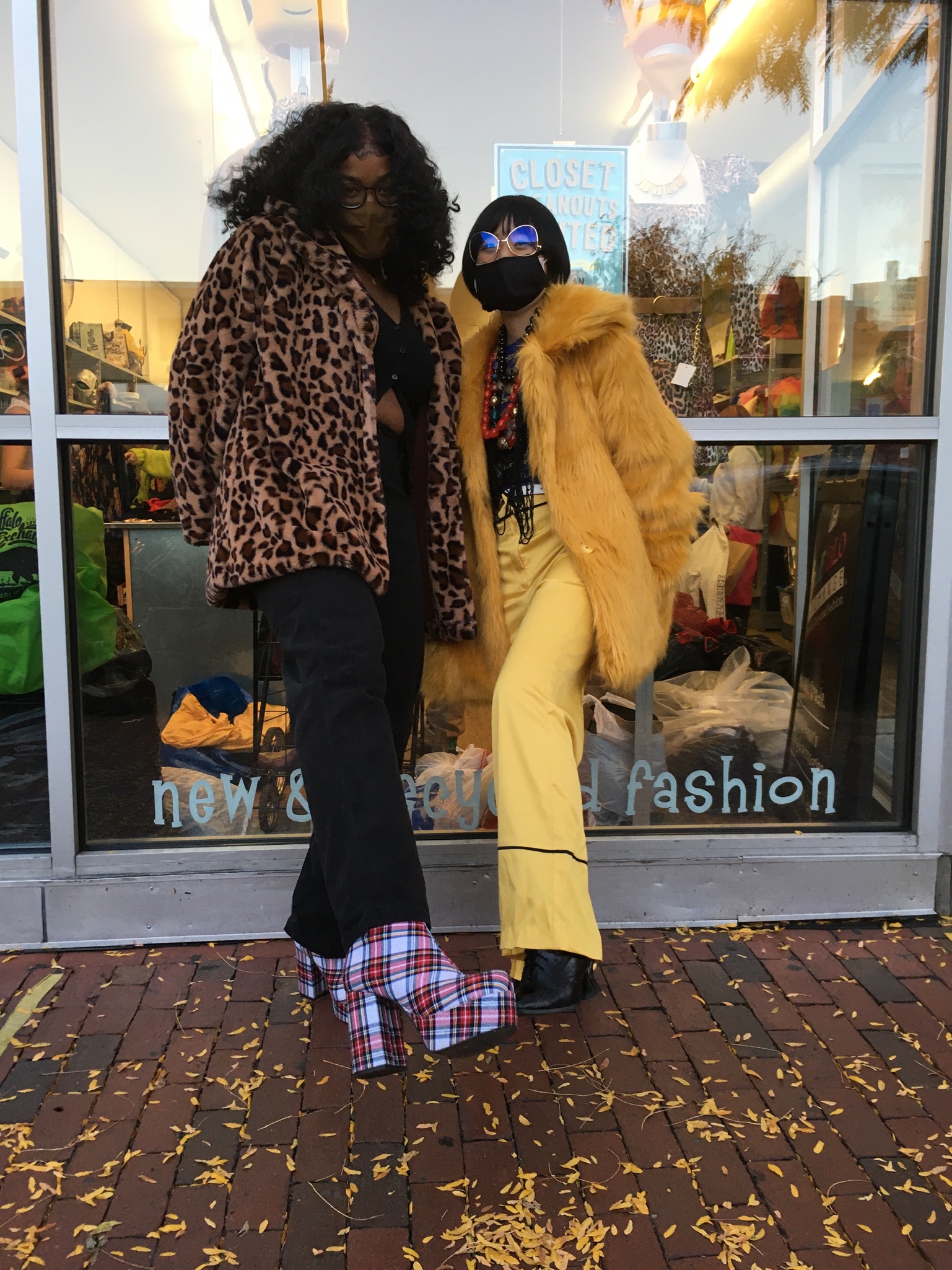 A person wearing a leopard print coat, black pants, and plaid boots, and another person wearing a yellow faux fur coat and yellow pants