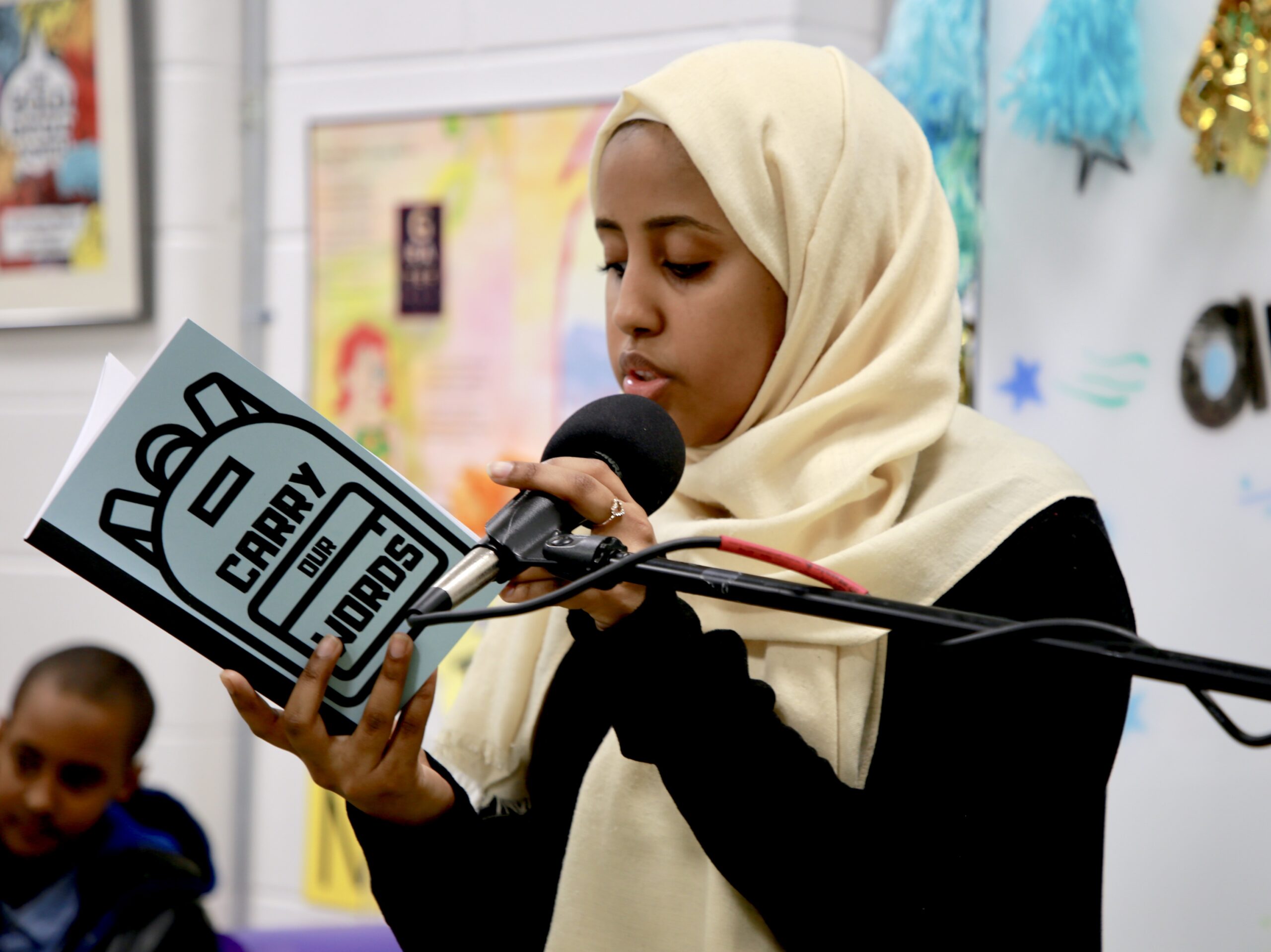 A woman holding a microphone and reading a book