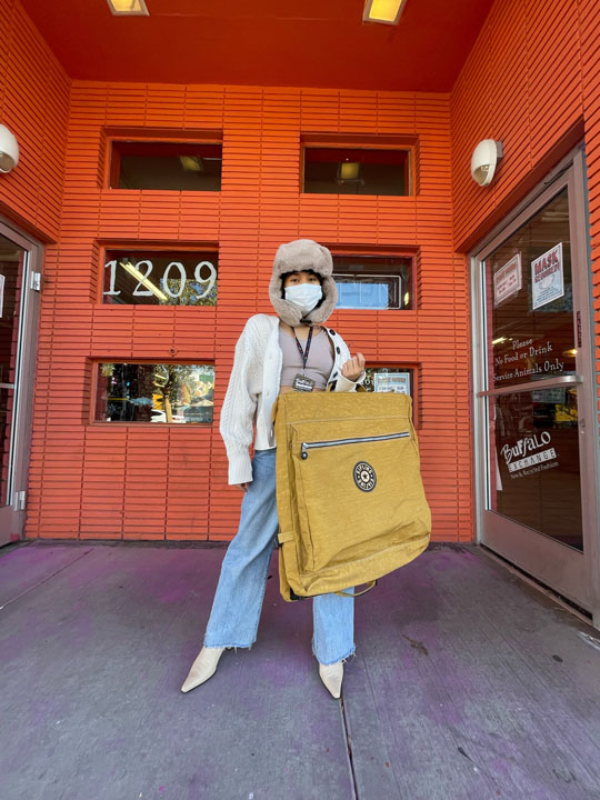 Girl in hat with a yellow oversized Kipling backpack