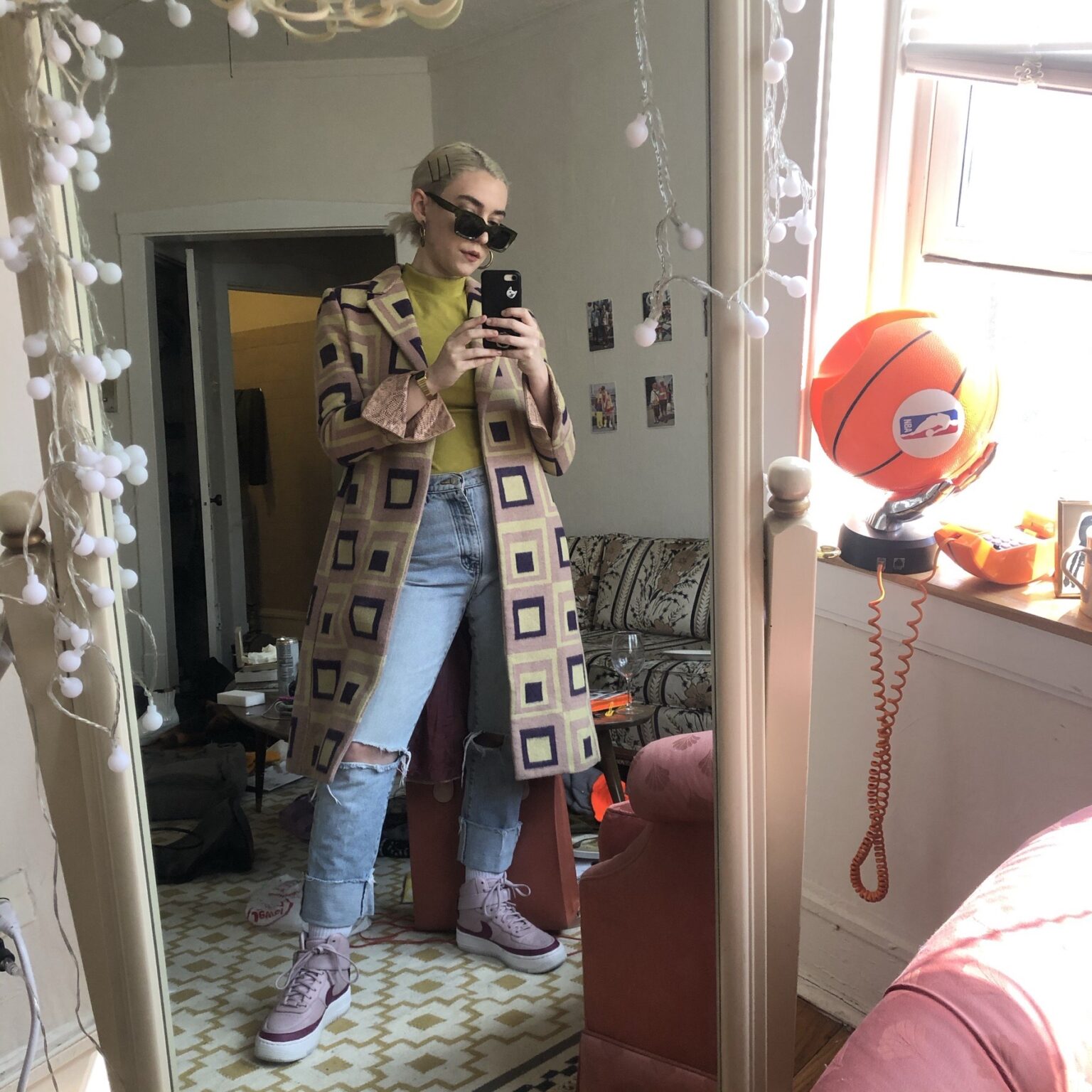 Flat lay of earth tone clothing including yellow ballcap, green jeans, brown suede boots, orange sweater and blue and orange plaid shirt