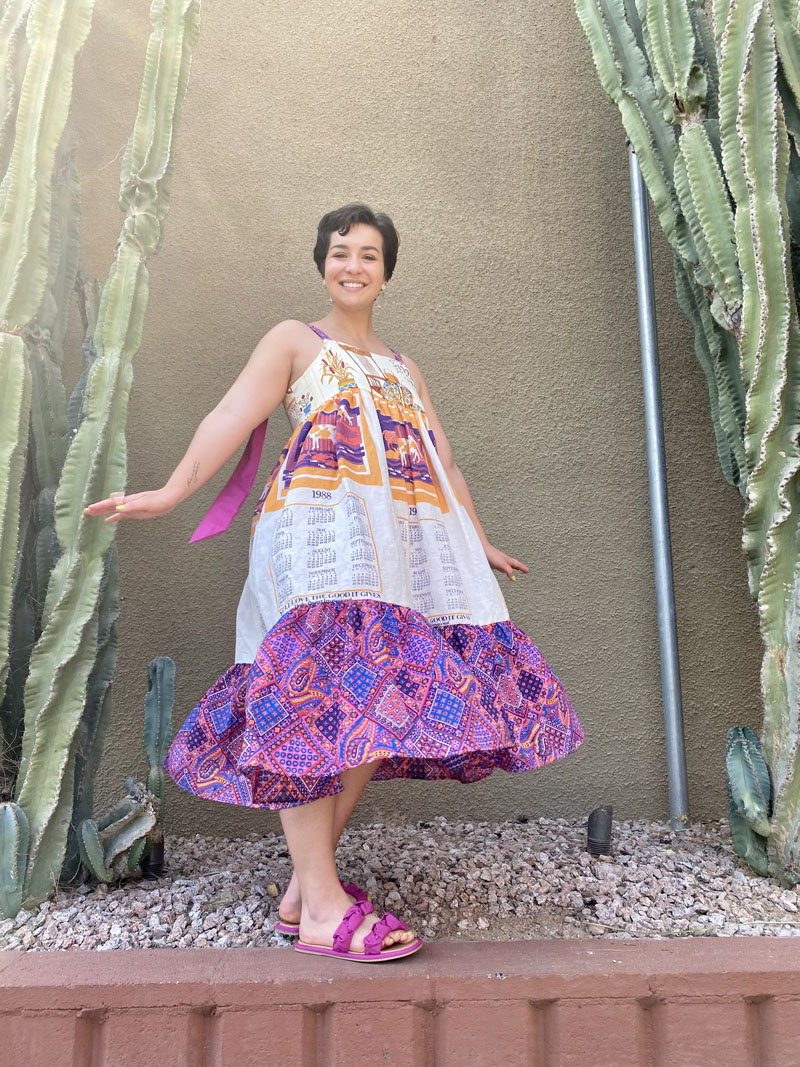 person posed mid-twirl wearing tiered, patterned mini dress with purple sandals