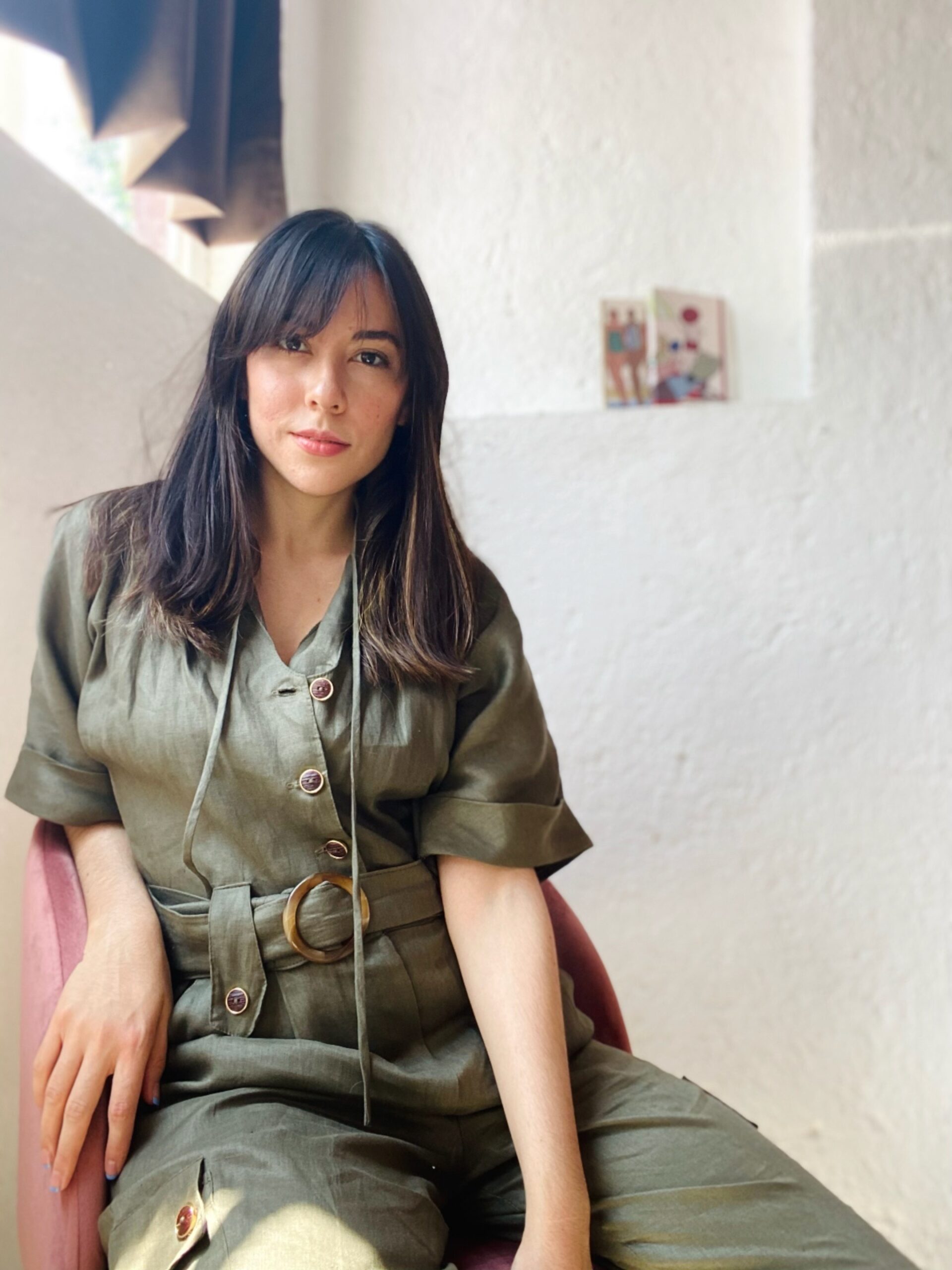 girl posing on a chair, she is wearing an army green jumpsuit