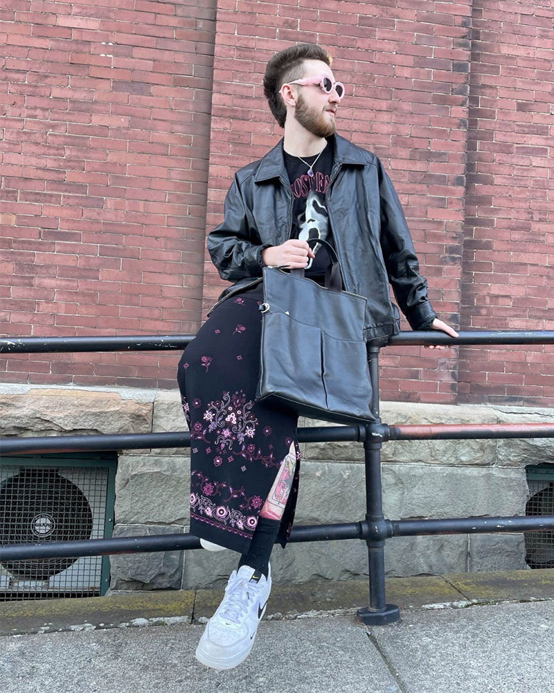 Person wearing black leather jacket styled with black maxi skirt and oversized tote bag