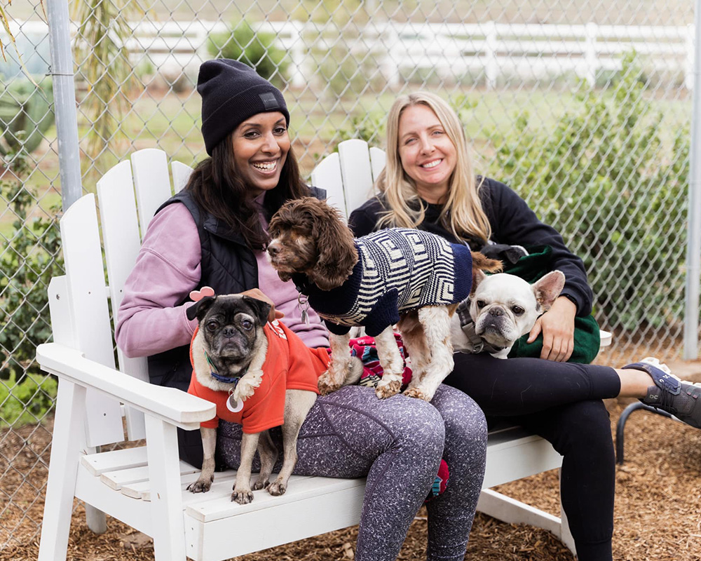 2 women sitting with 3 dogs in their laps