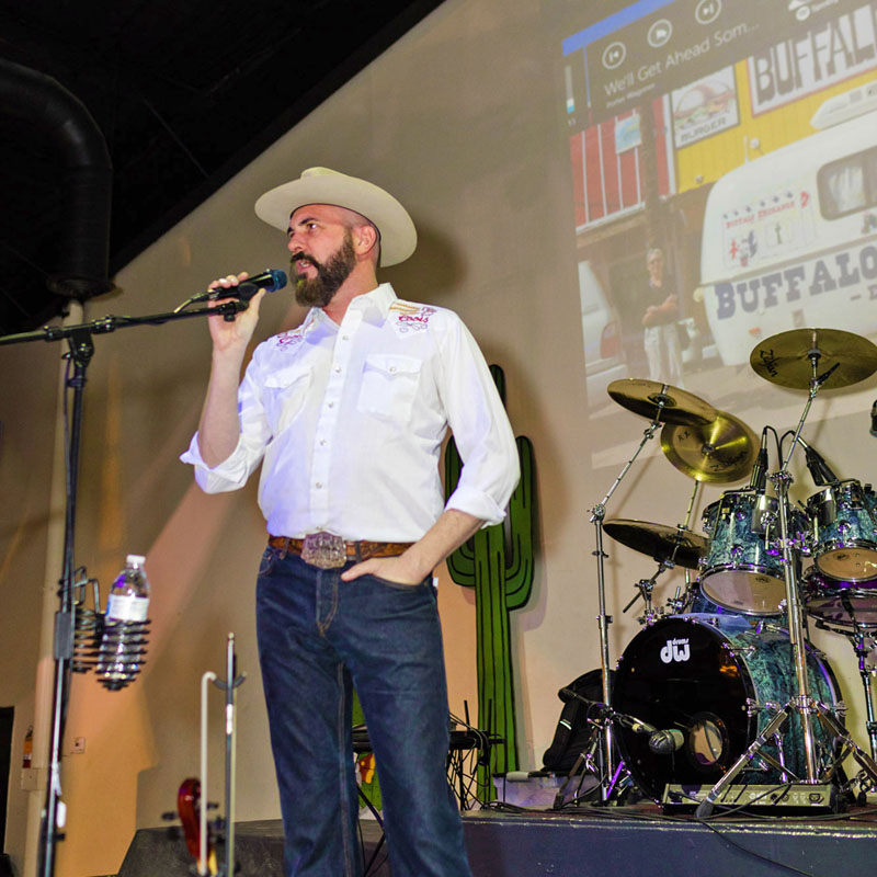 Joe on stage at a southwest-themed company meeting wearing a western outfit