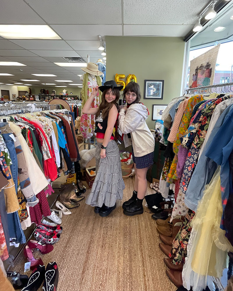 2 employees standing between racks of clothing