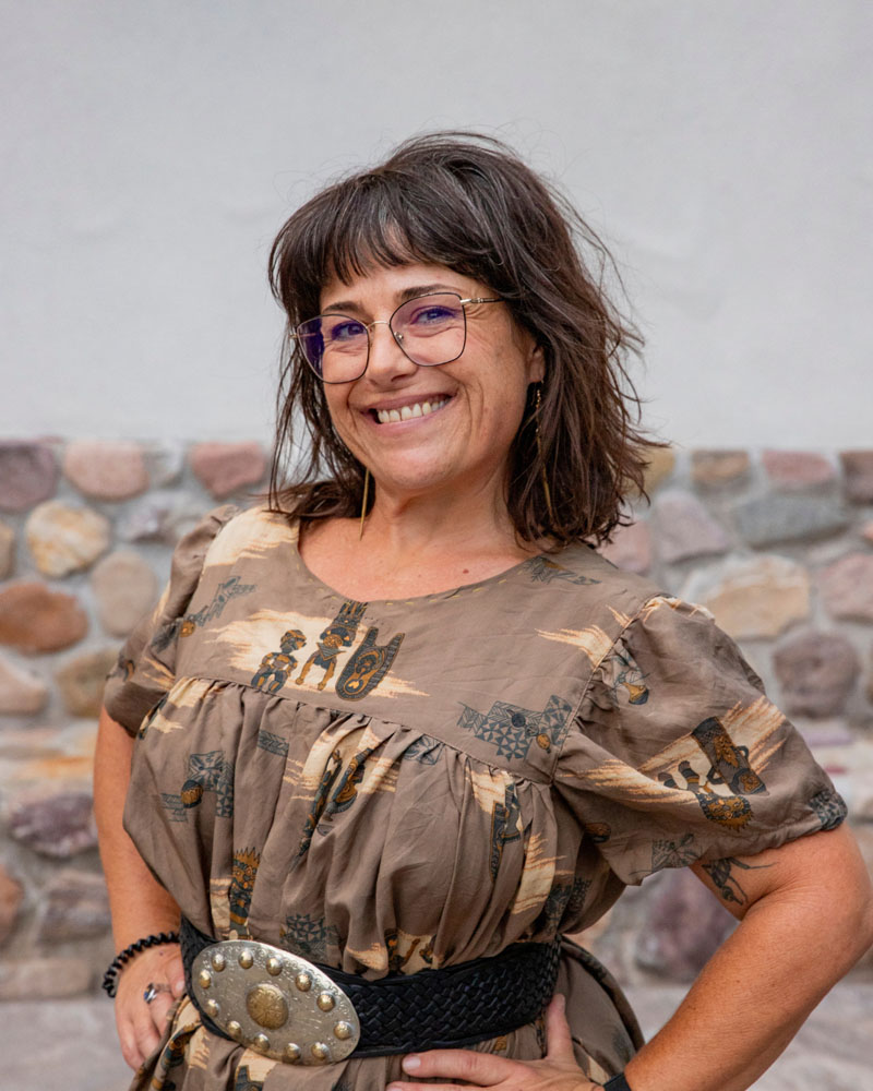 Photo of Denise smiling in a western print dress and leather belt