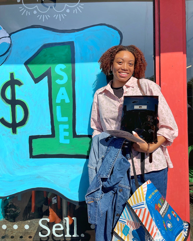 Customer by $1 sale sign holding a bundle of clothing