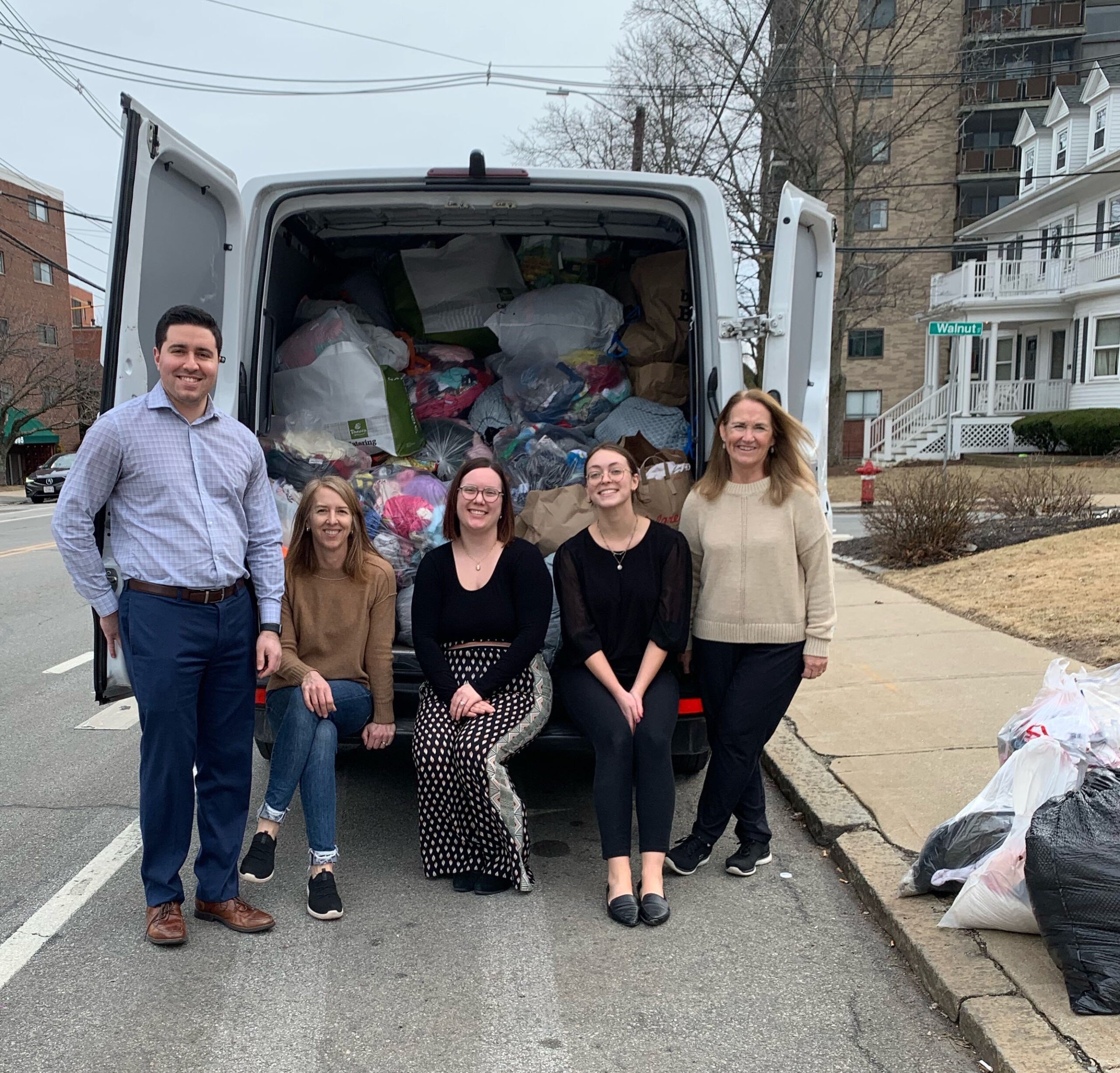 Volunteers posing in front of white van with filled with bags of donated clothes