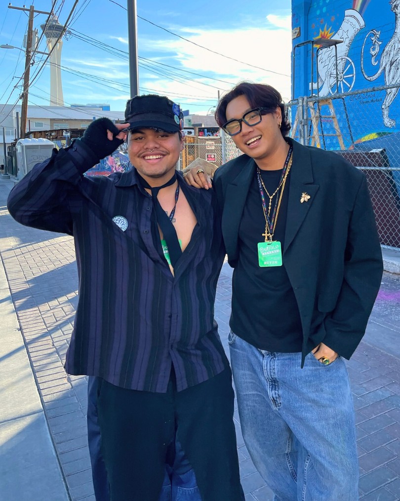 Two people laughing wearing business casual pieces like an oversized shirt and blazer styled with alt accessories including fingerless gloves, chains and baggy jeans Two people laughing wearing business casual pieces like an oversized shirt and blazer styled with alt accessories including fingerless gloves, chains and baggy jeans