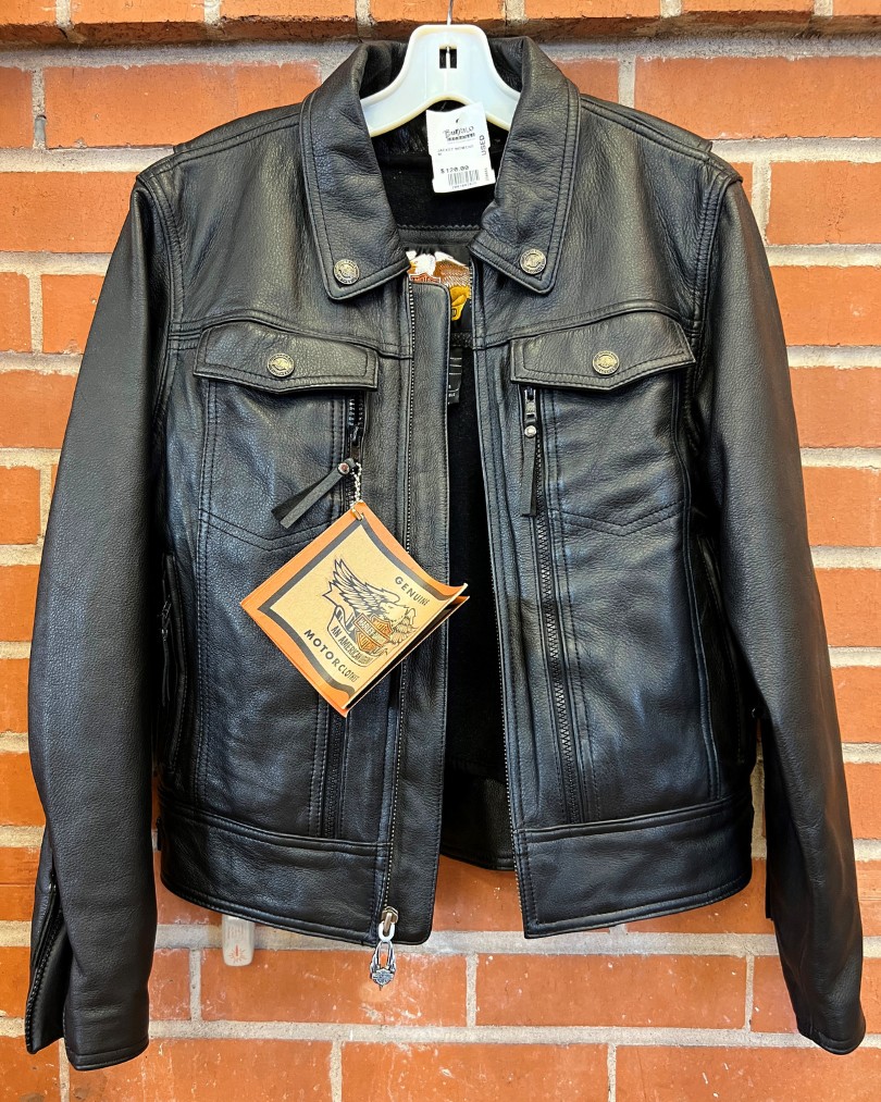 A brand new black leather Harley Davidson motorcycle jacket with tags attached hanging against a brick wall at Buffalo Exchange A brand new black leather Harley Davidson motorcycle jacket with tags attached hanging against a brick wall at Buffalo Exchange