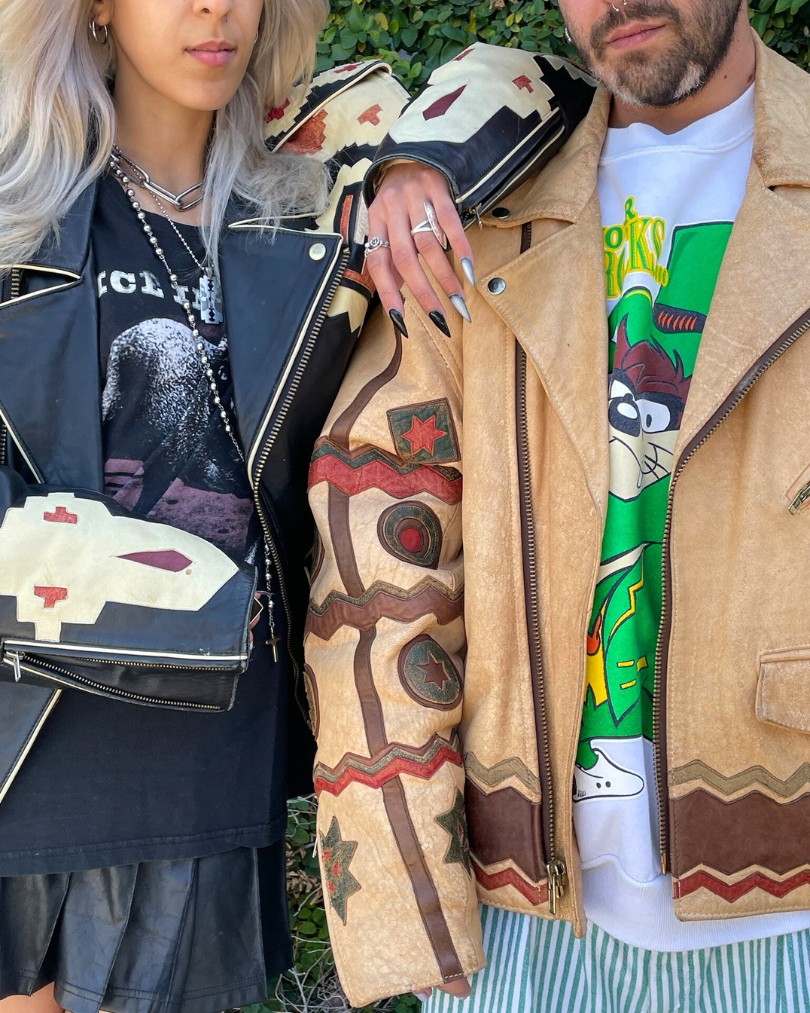 Two people posing outside in vintage leather jackets with western cutouts, styled with modern accents like graphic tee shirts and chunky silver jewelry Two people posing outside in vintage leather jackets with western cutouts, styled with modern accents like graphic tee shirts and chunky silver jewelry