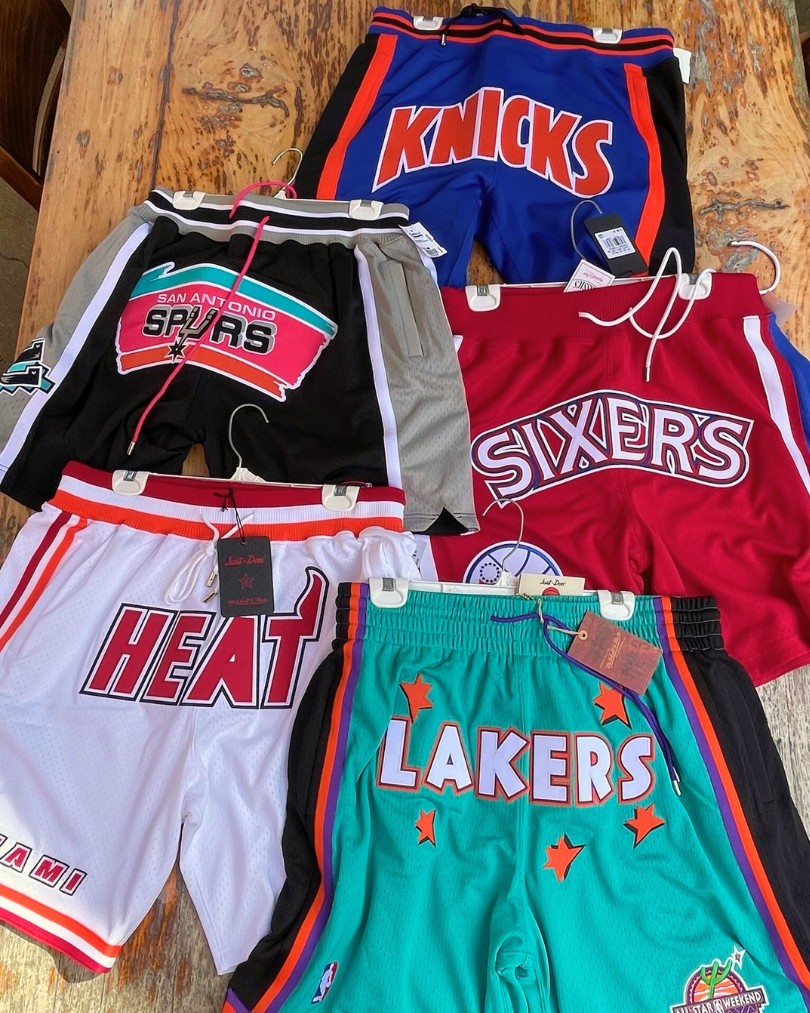 A collection of NBA-branded basketball shorts for teams like the New York Knicks, Miami Heat, Los Angeles Lakers, Philadelphia 76ers and San Antonio Spurs from Mitchell & Ness laid flat on a wooden table A collection of NBA-branded basketball shorts for teams like the New York Knicks, Miami Heat, Los Angeles Lakers, Philadelphia 76ers and San Antonio Spurs from Mitchell & Ness laid flat on a wooden table