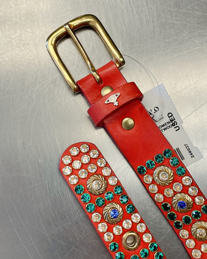 Coral red belt from Vivienne Westwood with colorful white, green, and blue rhinestones on the buy counter at Buffalo Exchange Coral red belt from Vivienne Westwood with colorful white, green, and blue rhinestones on the buy counter at Buffalo Exchange